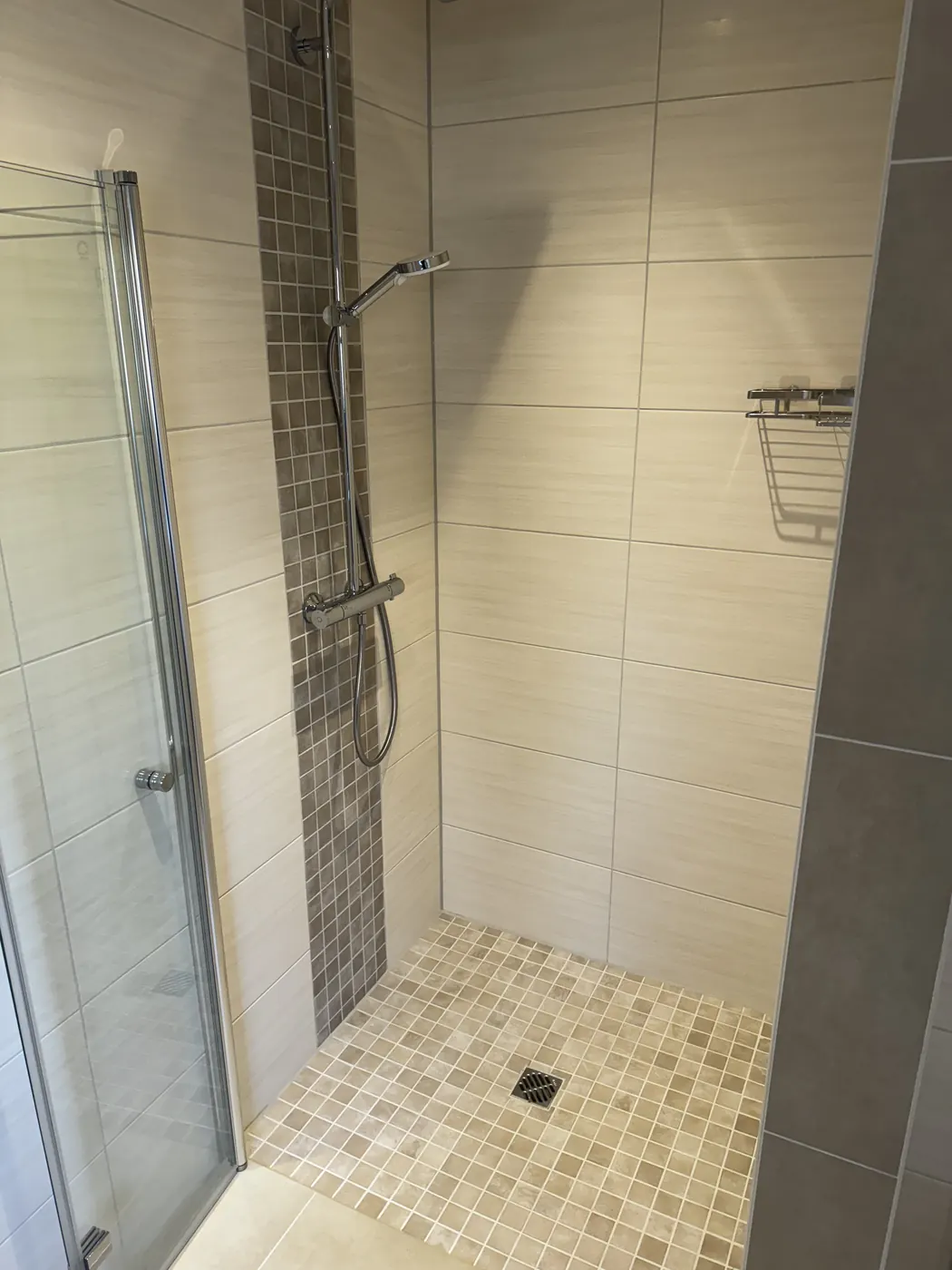 Dusche mit Mosaikboden und Glastür