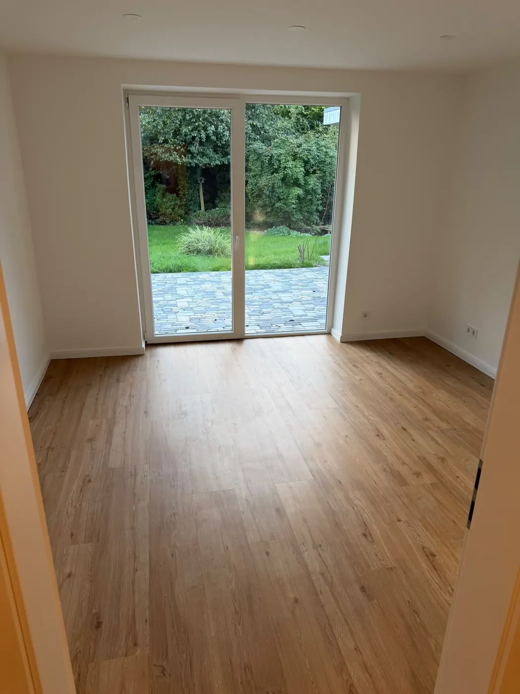 Renovierter Wohnraum mit neuem Boden und Terrassentür